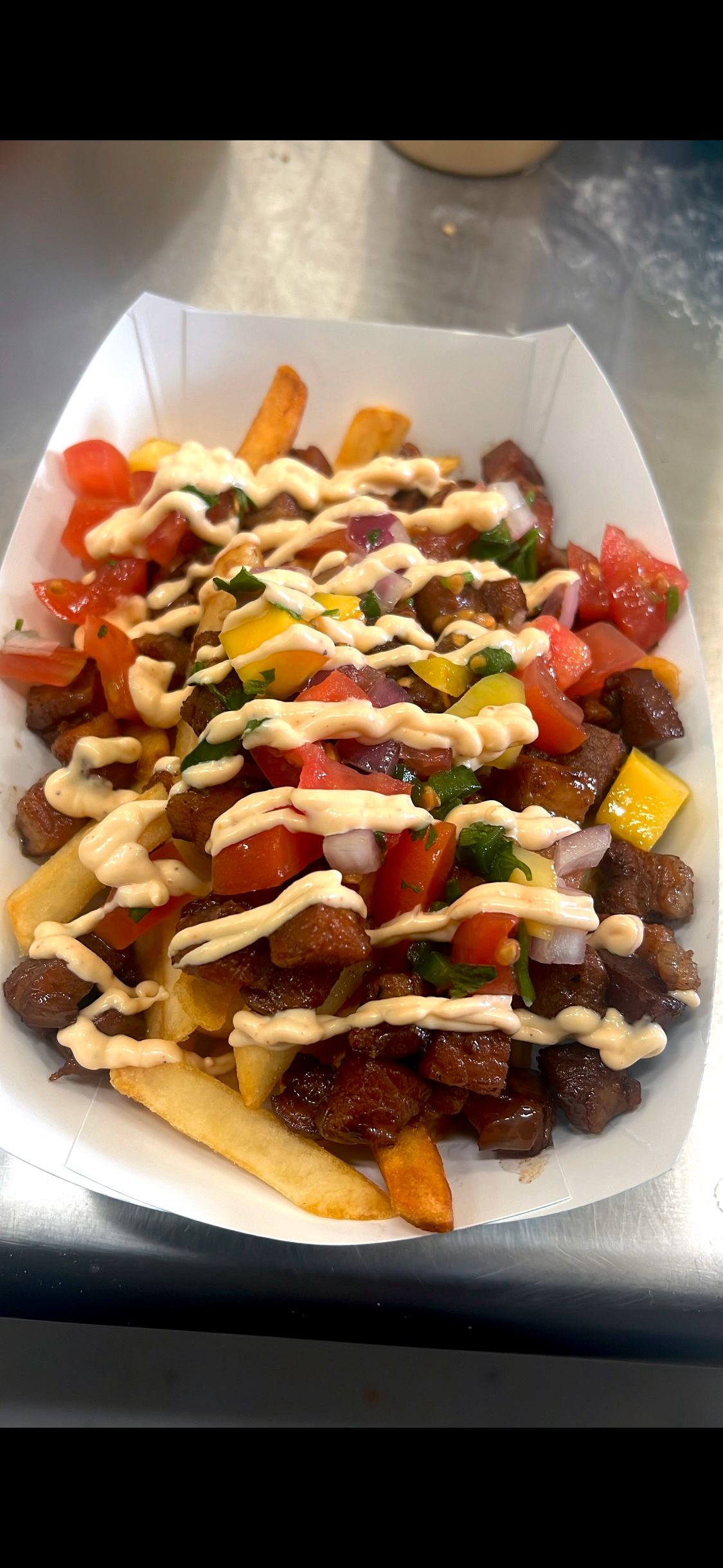 Delicious sisig fries loaded with pork belly, peppers, and sauces